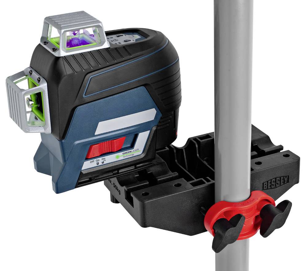Ett lasernivåinstrument är fäst vid en vertikal stolpe och projicerar gröna laserlinjer, vilket används för precis nivellering och justering vid byggnadsarbeten.