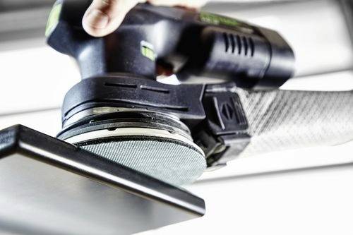 En närbild av en elektrisk slipmaskin i bruk, som jämnar till en träyta. En hand griper fast verktyget stadigt och belyser dess funktionalitet.