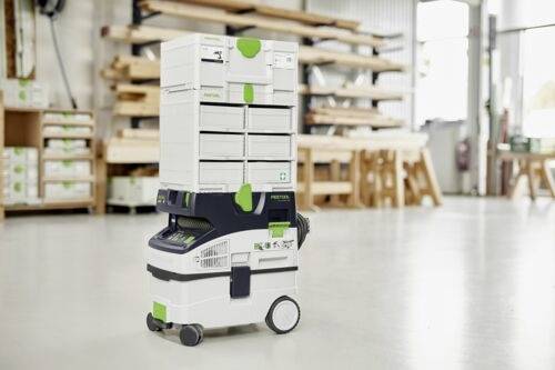 Ett mobilt verkstadssystem med staplade verktygslådor på hjul, i en verkstadsmiljö med träställ i bakgrunden.