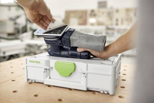 En person håller i en Festool excenterslip ovanför en arbetsbank. En annan hand justerar sliparens slipdyna. Slipen vilar på en Festool verktygsväska.