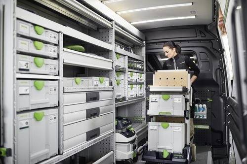 En person organiserar lådor och tillbehör inuti en välutrustad leveransbil med hyllor, lådor och olika förvaringsutrymmen.