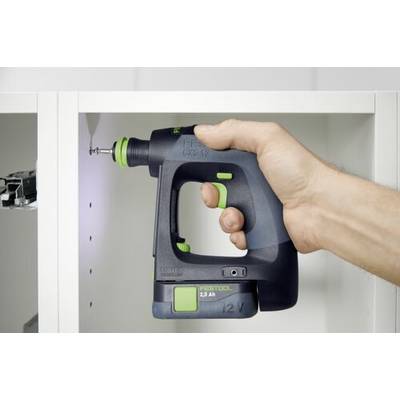 En person använder en sladdlös borrmaskin för att skruva fast en skruv i ett vitt skåp. Borrmaskinen är svart med gröna detaljer och märkt 'FESTOOL 12V'.