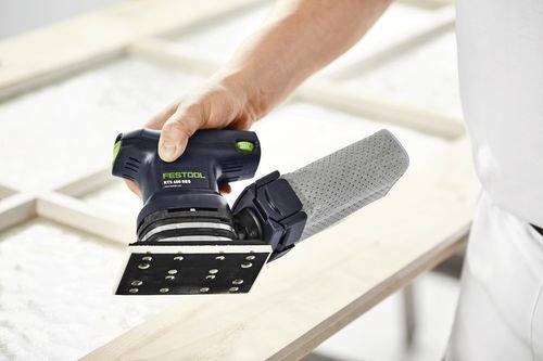 En person använder en Festool excenterslip på en träyta och jämnar ut materialet. Slipmaskinen har en dammuppsamlingspåse ansluten.