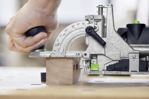 En hand manövrerar ett träbearbetningsverktyg som skär ett exakt spår i ett träblock på en arbetsyta, med betoning på hantverksskicklighet och precision.