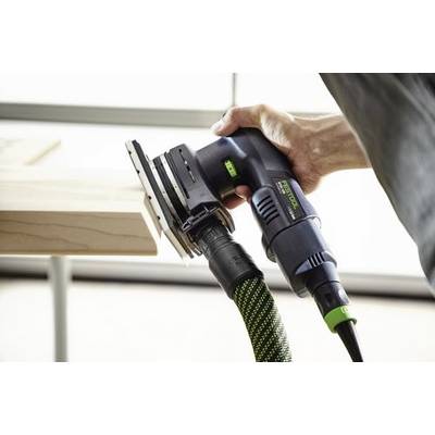 En person använder en elektrisk slipmaskin på en träyta och håller verktyget med en hand. Slipmaskinen är ansluten till en grön och svart slang.