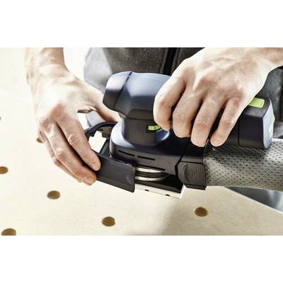 Händer som använder en elektrisk slipmaskin på en träyta med jämnt fördelade hål, med fokus på att jämna ut materialet.