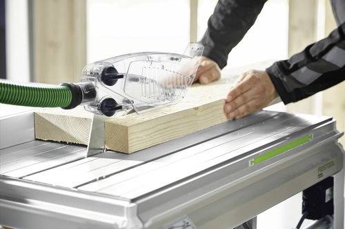 En person använder en bordssåg för att såga en träplanka, med händerna som styr träet och ett tydligt bladskydd som säkerställer säkerheten under användningen.