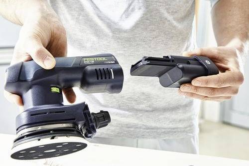 En person sätter i ett batteri i en sladdlös orbital slip, som visar dess bärbarhet och användarvänlighet på en ljus arbetsyta.