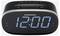 En digital väckarklocka som visar '12:00', med knappar för inställning, förinställningar, tid, volym och ljusstyrka på ovansidan.
