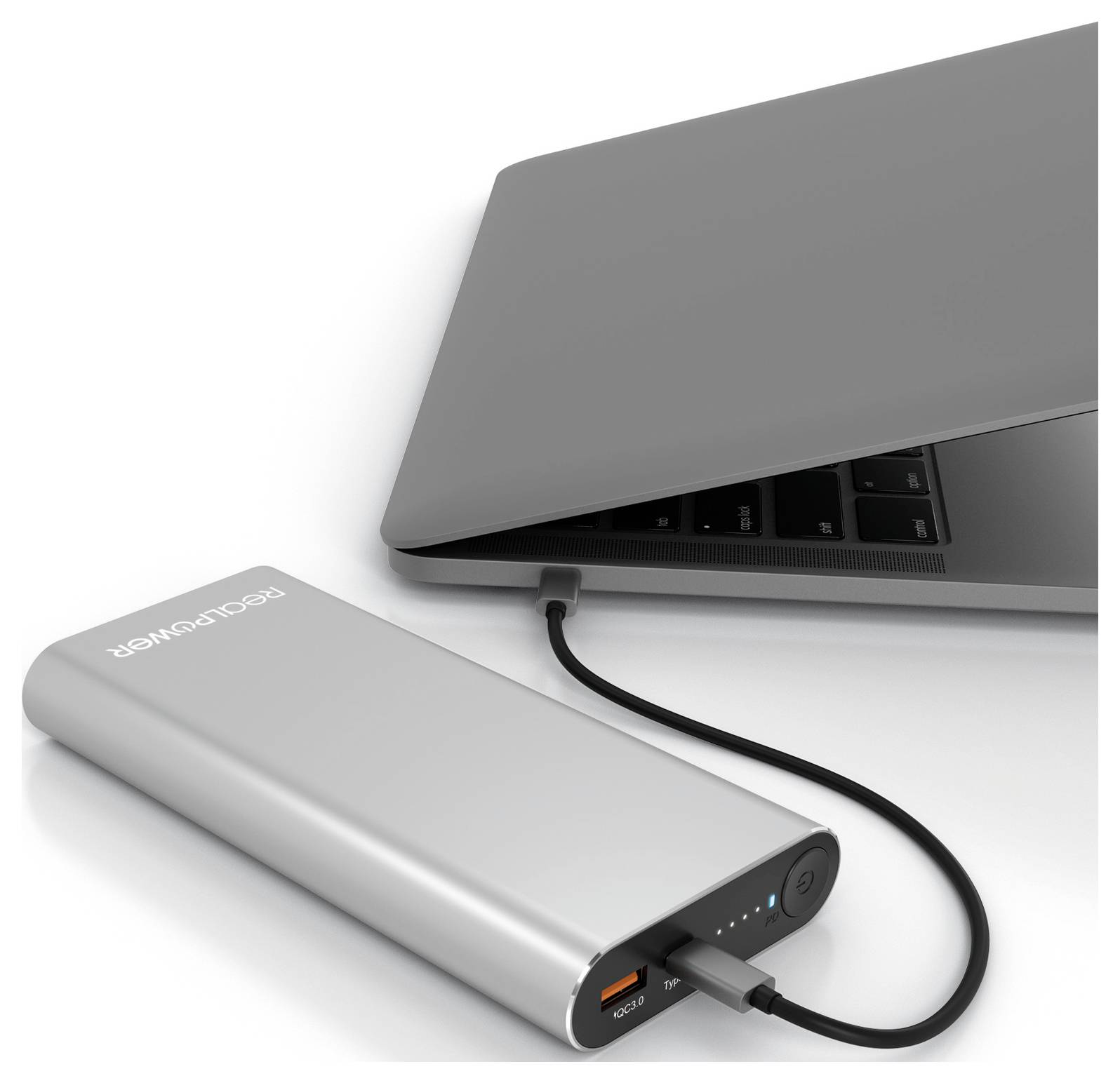 En silverfärgad powerbank ansluten till en stängd bärbar dator med en svart kabel, som visar laddningsstatus på powerbanken.