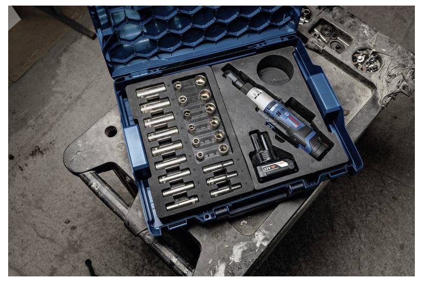 En blå verktygslåda öppen på ett bord, innehållande ett elverktyg med flera tillbehör och ett batteripaket, avsett för borrning eller fästning.