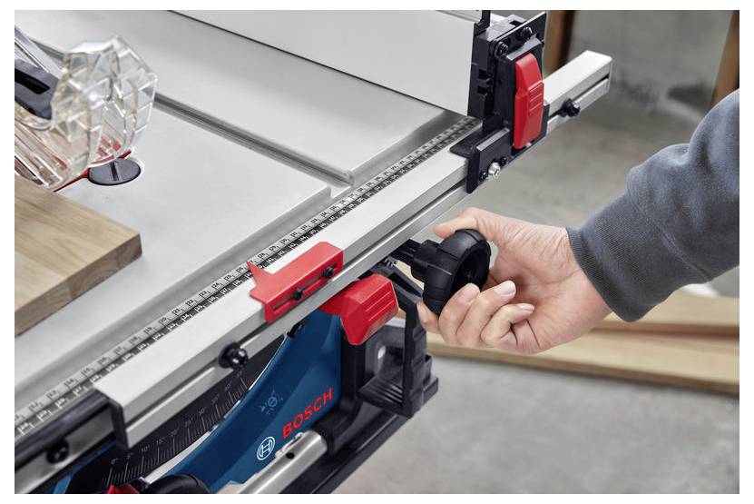 En person justerar stängslet på en Bosch bordssåg i en verkstad och visar precision och kontroll över verktyget.