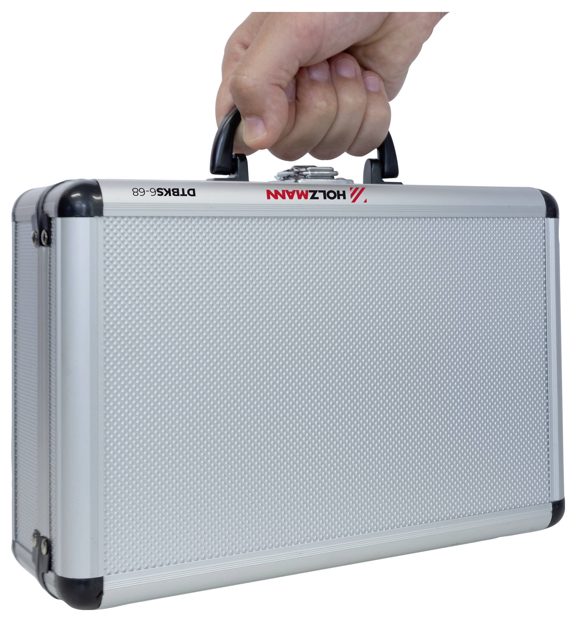 En hand håller en liten, silverfärgad, strukturerad portfölj med svarta hörn. Portföljen har ett handtag och är märkt med röd och svart text.