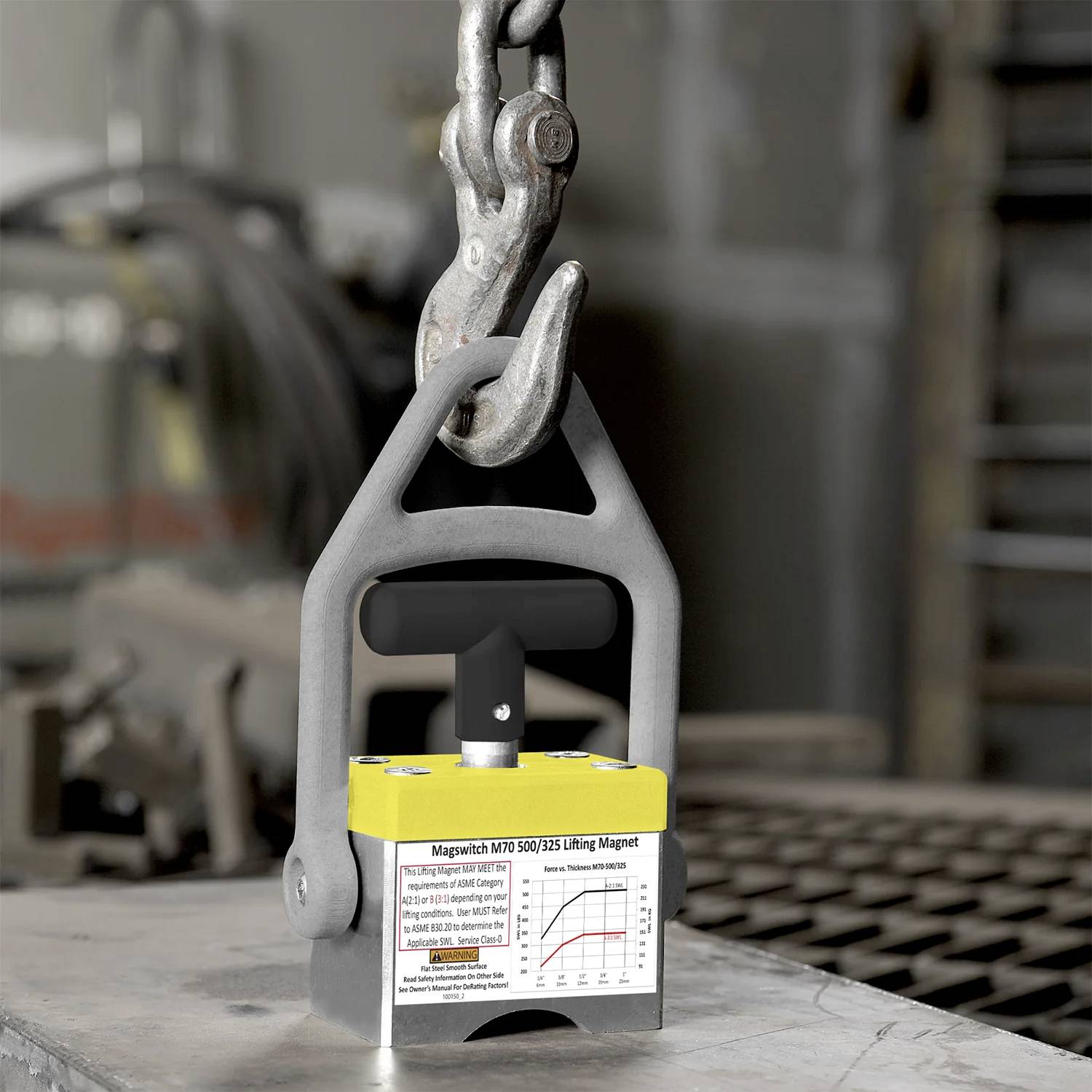 En metalllyftmagnet med ett handtag är fäst vid en metallkedja. Etiketten på magneten anger ett modellnummer och lyftkapacitet.