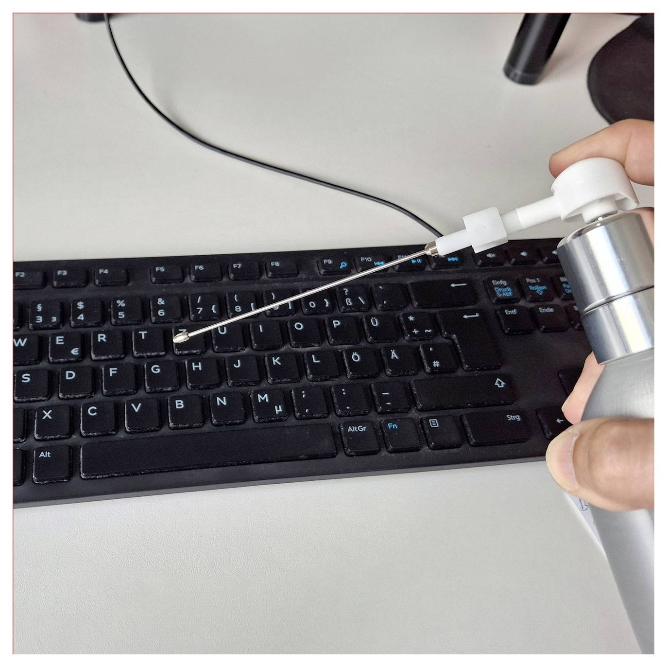 En burk komprimerad luft som används för att rengöra damm från ett datortangentbord. Munstycket är riktat mellan tangenterna.