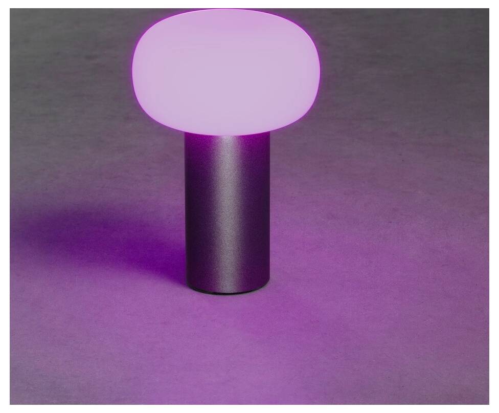 En liten bordslampa med en ogenomskinlig oval rosa lysande topp och en cylindrisk metallisk bas, som kastar ett mjukt rosa sken på en slät yta.