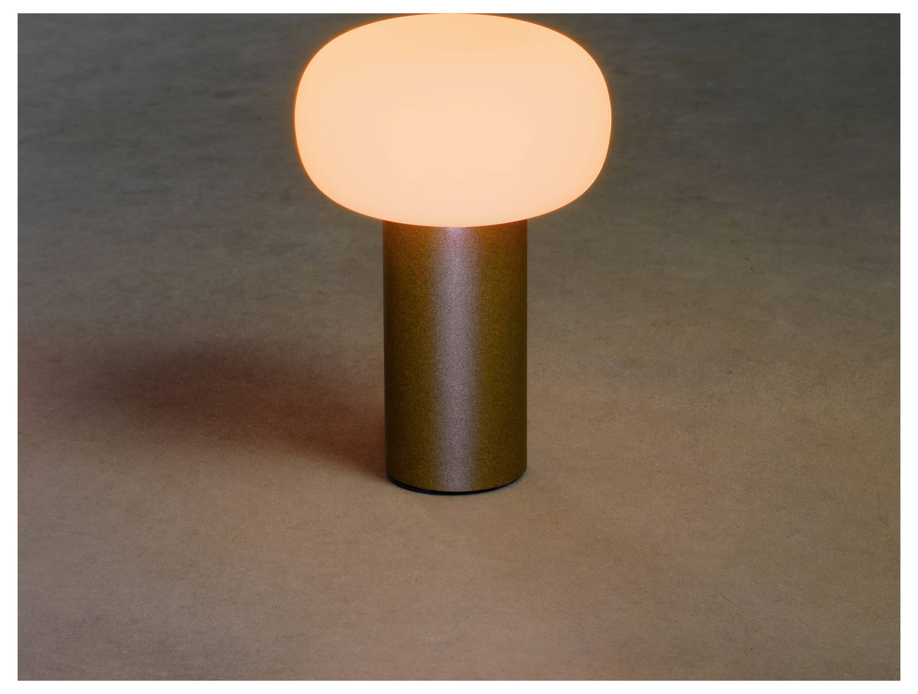 En modern bordslampa med en glödande, slät, oval skärm vilar på en cylindrisk bas och utstrålar ett varmt, omgivande ljus.