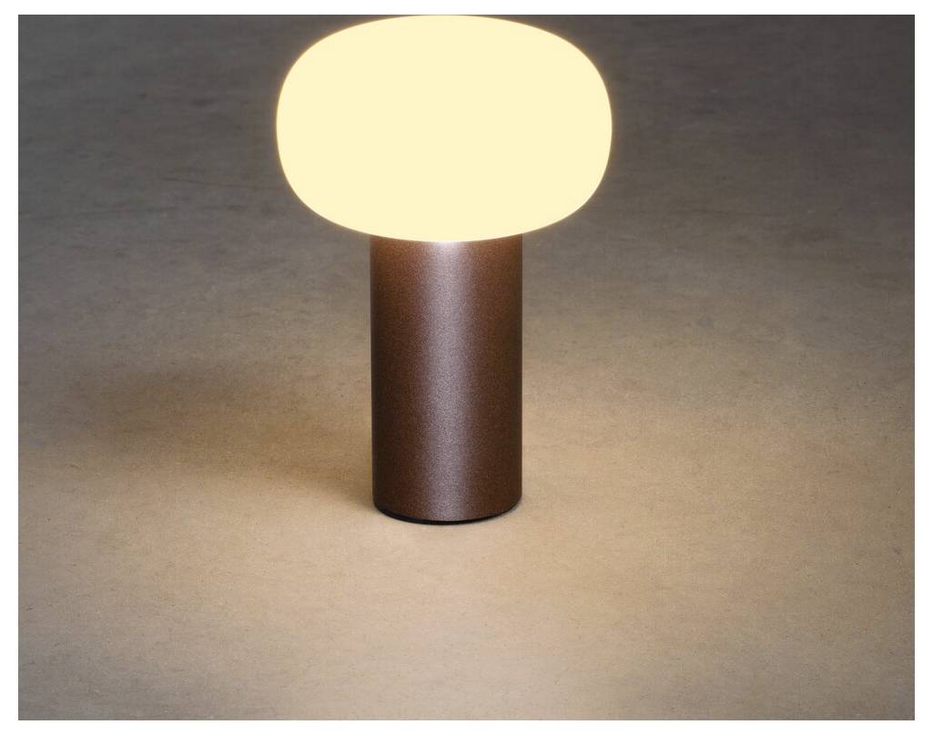 En modern bordslampa med en rund, vitglödande skärm som vilar på en cylindrisk bronserad bas, som kastar ett varmt ljus på en neutral yta.
