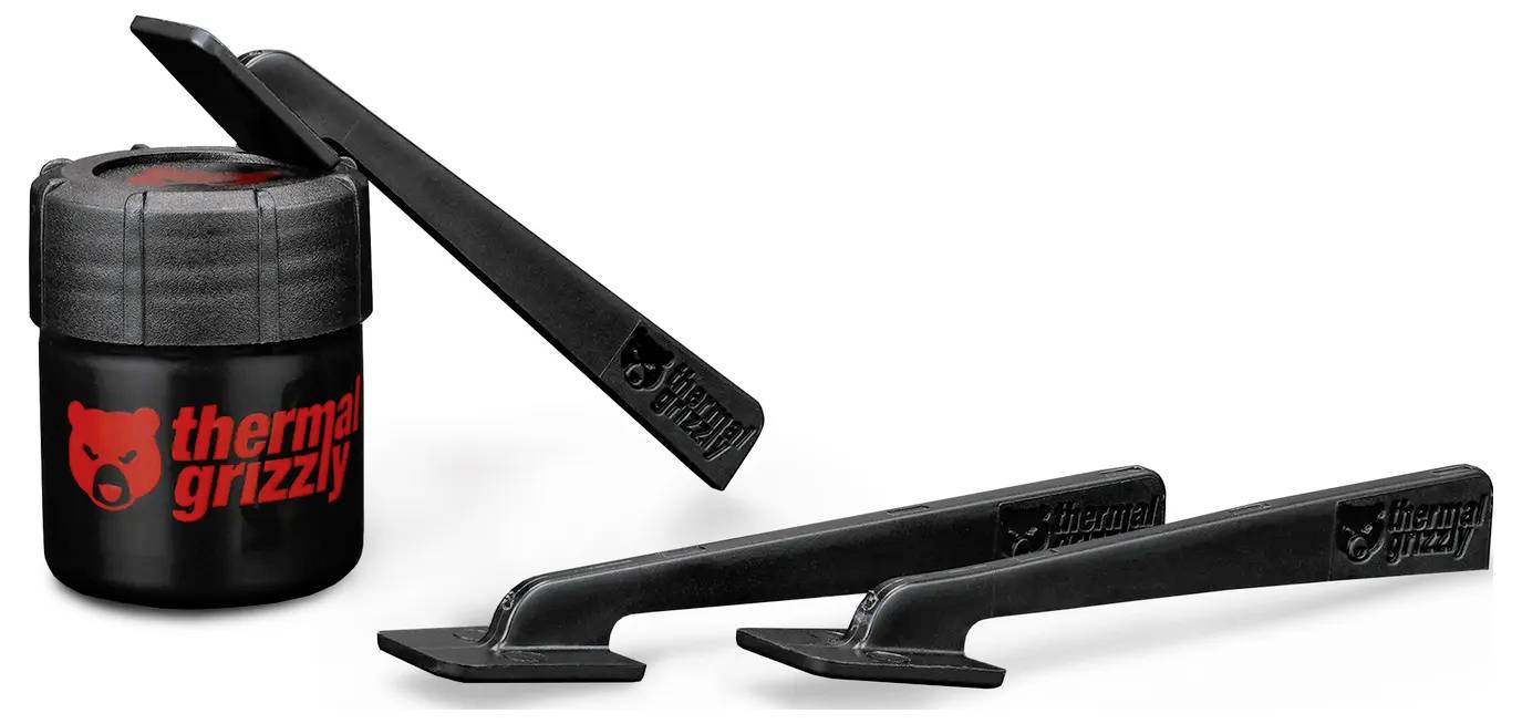 En liten svart behållare med 'thermal grizzly' logotypen ligger bredvid tre svarta appliceringsverktyg. Alla föremål är placerade på en vit bakgrund.