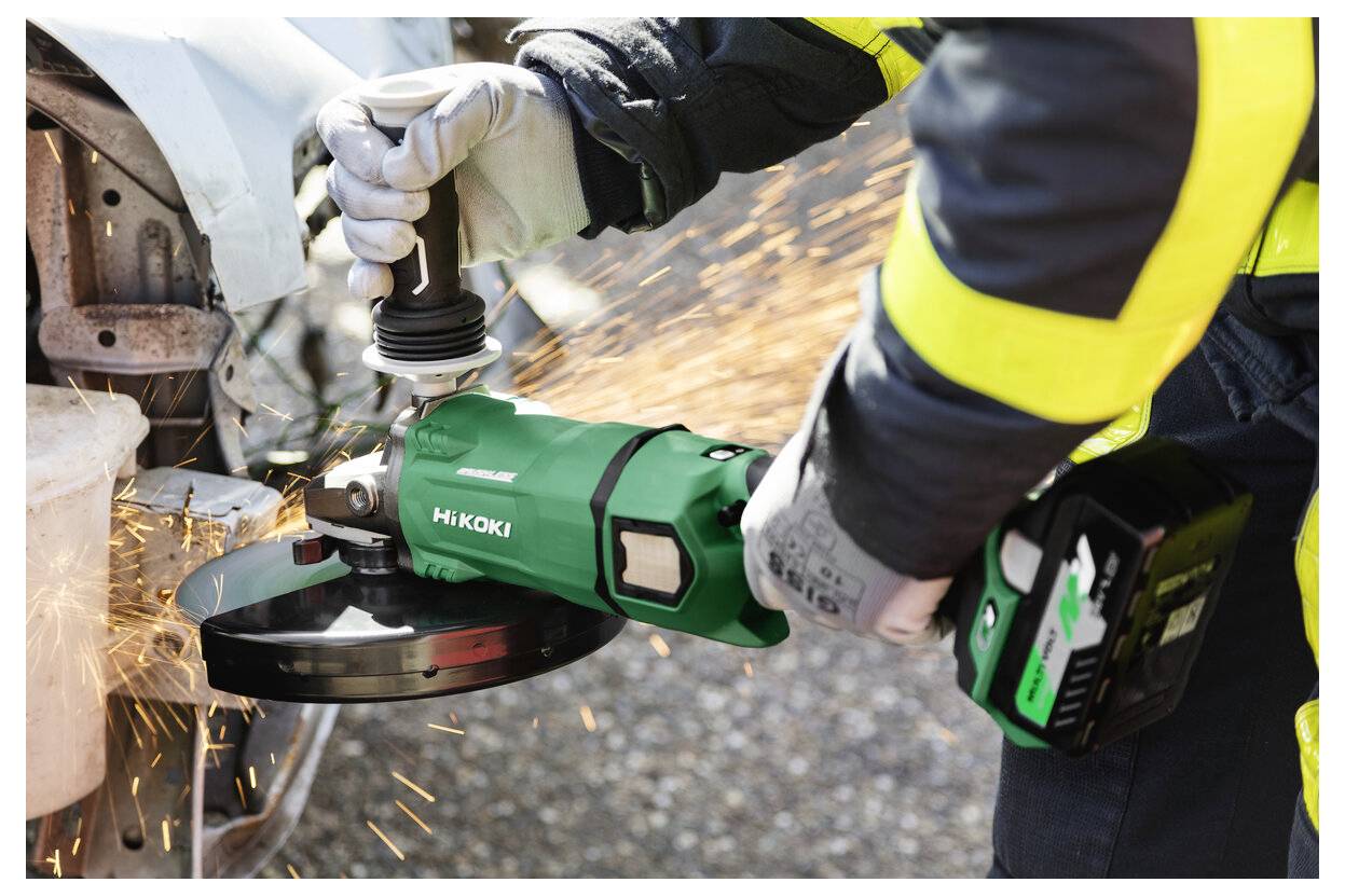 En person som bär skyddsutrustning använder ett grönt elverktyg för att skära metall på ett fordon, vilket skapar gnistor.