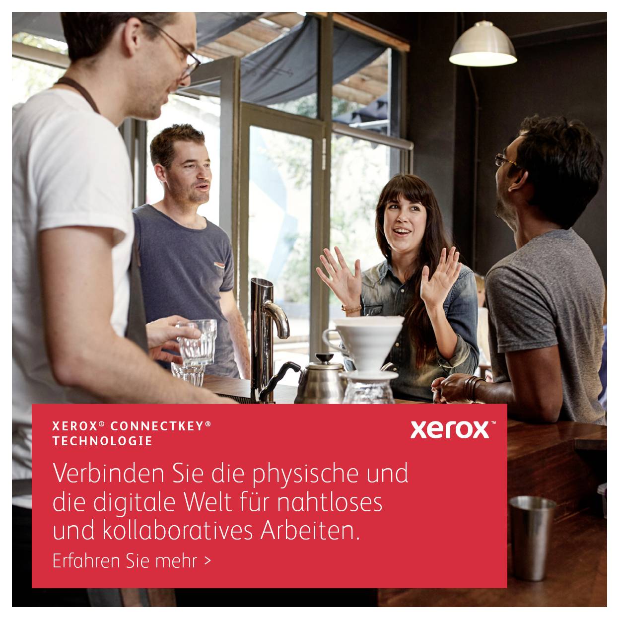 En grupp på fyra personer samtalar i ett kök. I förgrunden finns en skylt med texten 'Xerox ConnectKey Teknologi'.