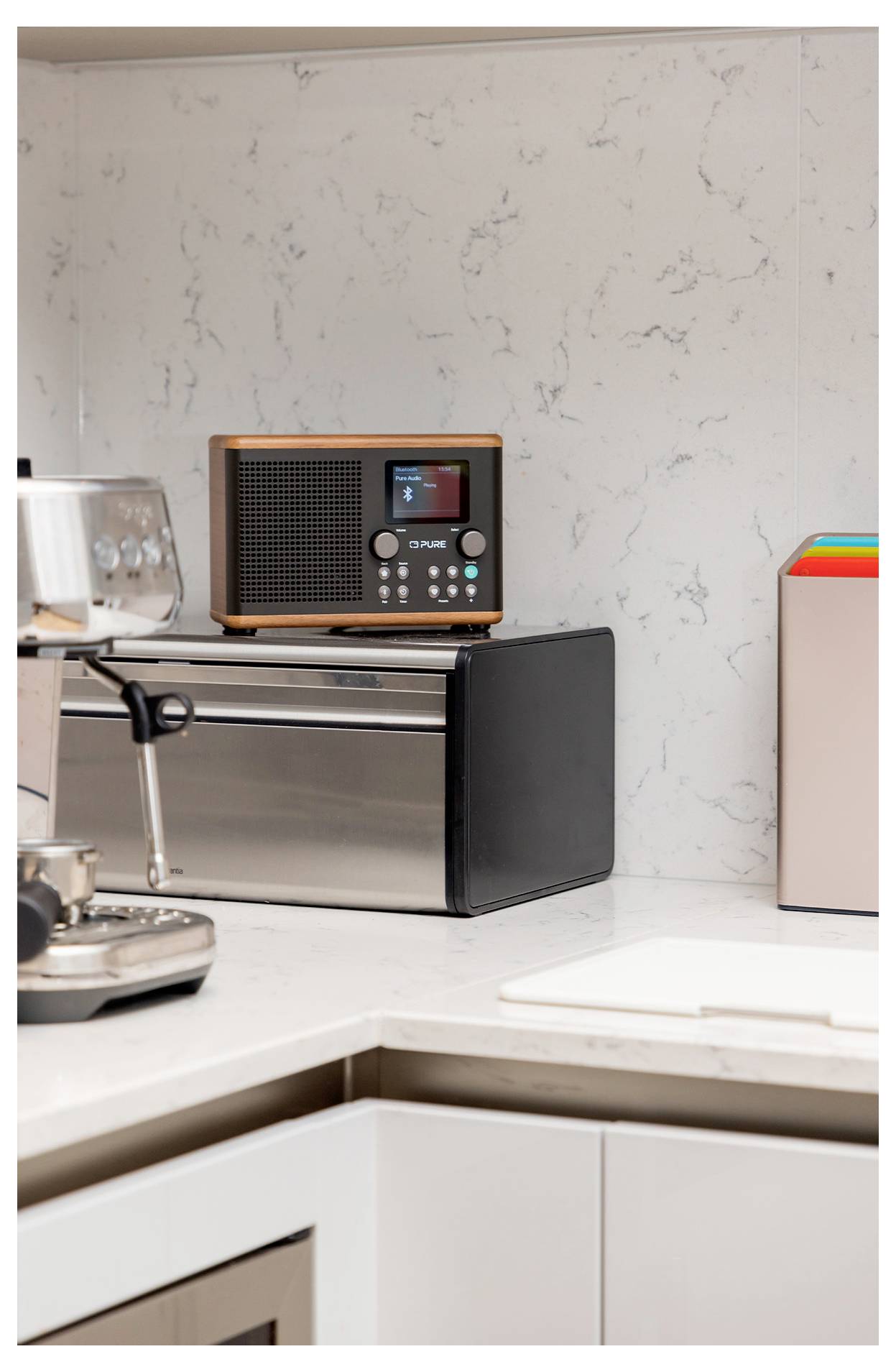 Ett modernt köksbänkskiv med en retro-radioapparater och en rostfri apparat. En kaffebryggare är delvis synlig till vänster.