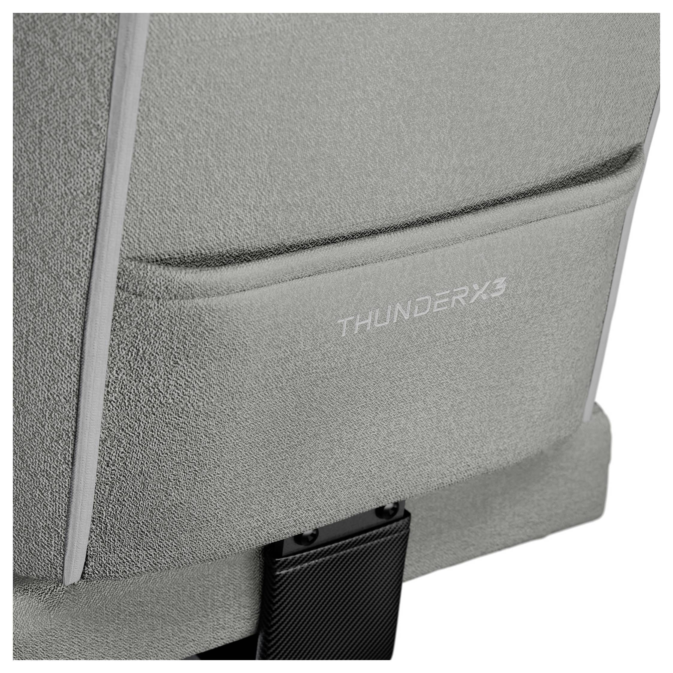 En närbild av en grå stols ryggstöd, med 'THUNDERX3' logotyp broderad i vitt. Tyget ser texturerat och detaljerat ut.