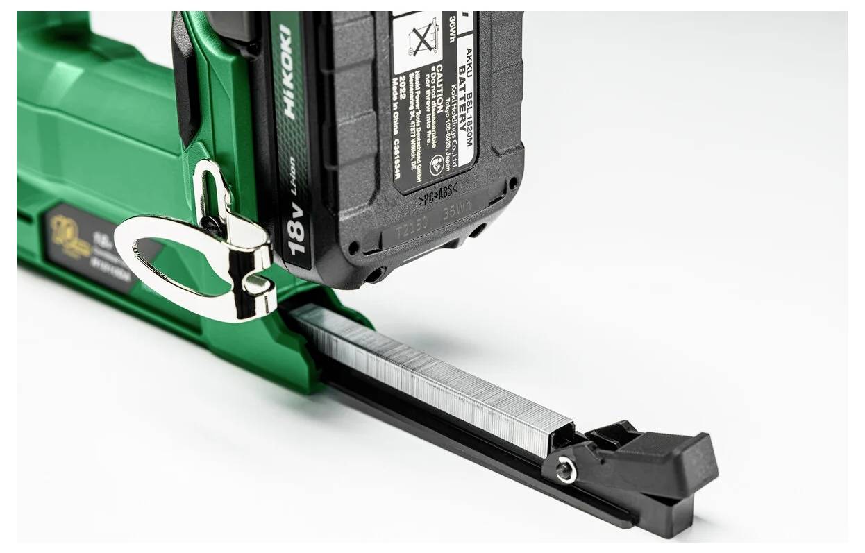 En grön och svart elverktyg med ett 18V-batteri, redo med spikar för användning.