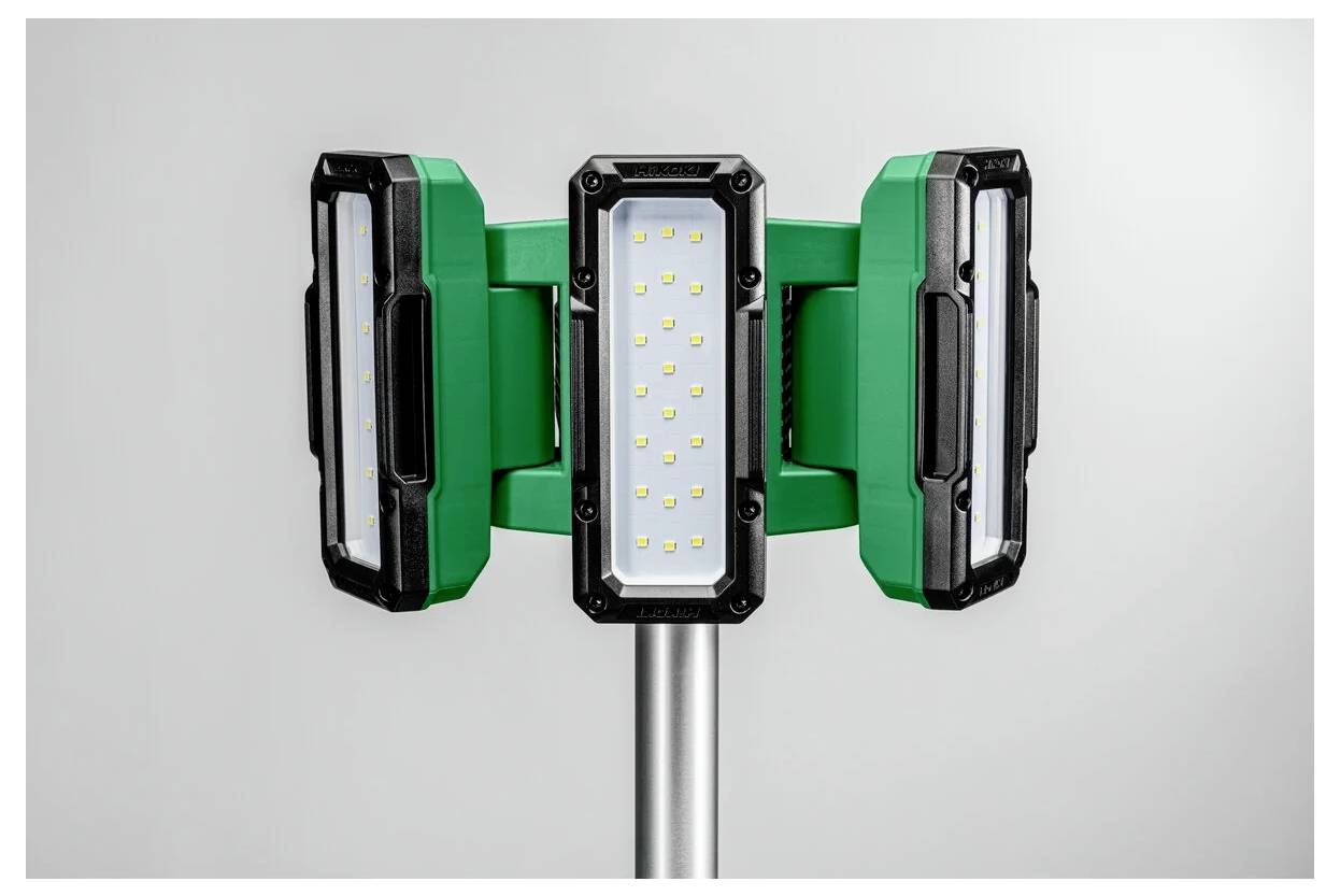 En grön och svart trepanels LED-arbetsbelysning på ett silverfärgat stativ, designad för stark, bred belysning i industriella miljöer.