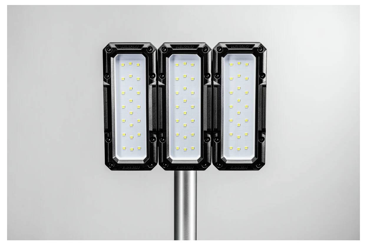 Trestegad LED-gatulampa med rektangulära svarta ramar och gula LED-lampor på en silverfärgad stolpe, placerad mot en enfärgad bakgrund.