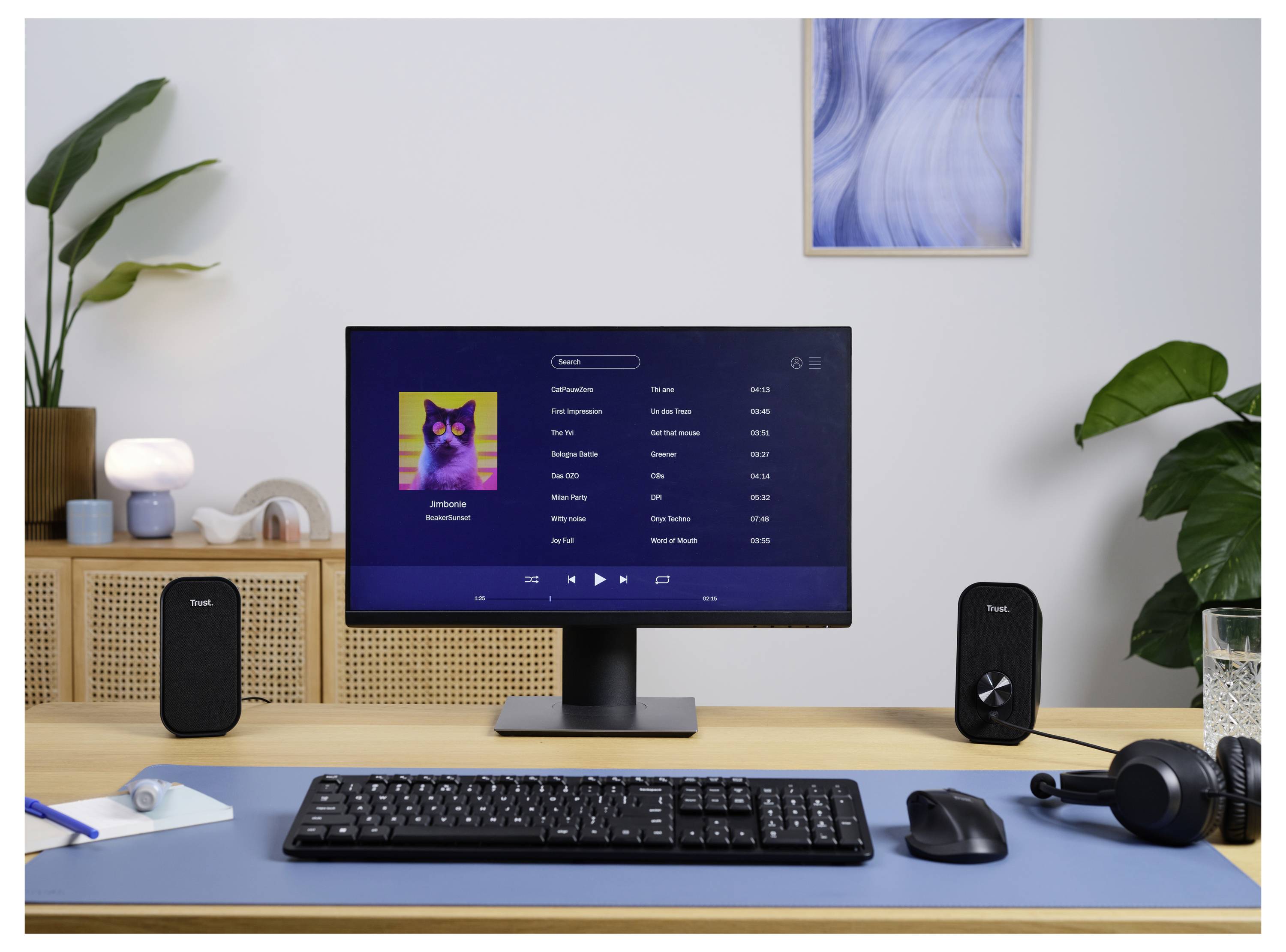 En datorskärm visar en musikspelarsapp med ett albumomslag och en låtlista. Kringliggande föremål inkluderar högtalare, ett tangentbord, en mus och växter.