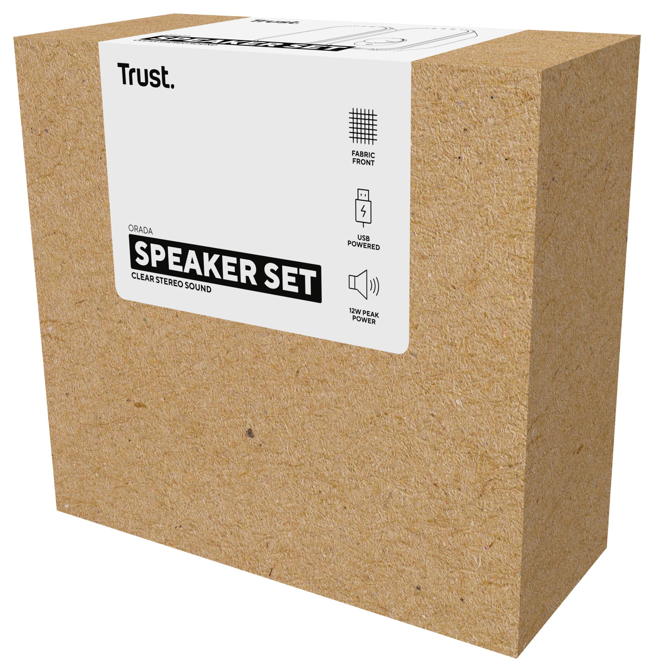 En kartong innehållande ett 'Speaker Set' från Trust visas. Etiketten framhäver funktioner som 'Kristallklar stereoljud,' 'USB-driven' och 'Textilfront.'