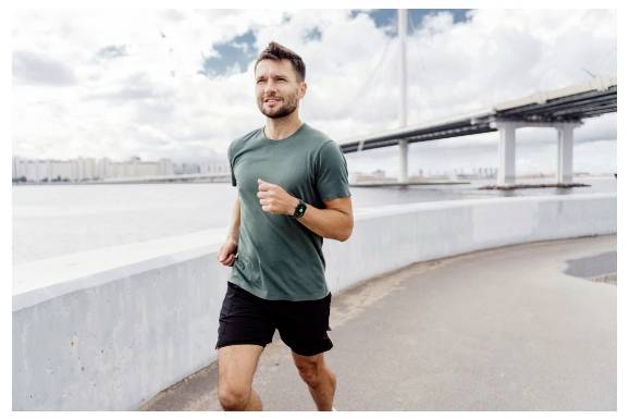 En man i en grön tröja joggar längs en flodstig med en bro i bakgrunden under en molnig himmel.