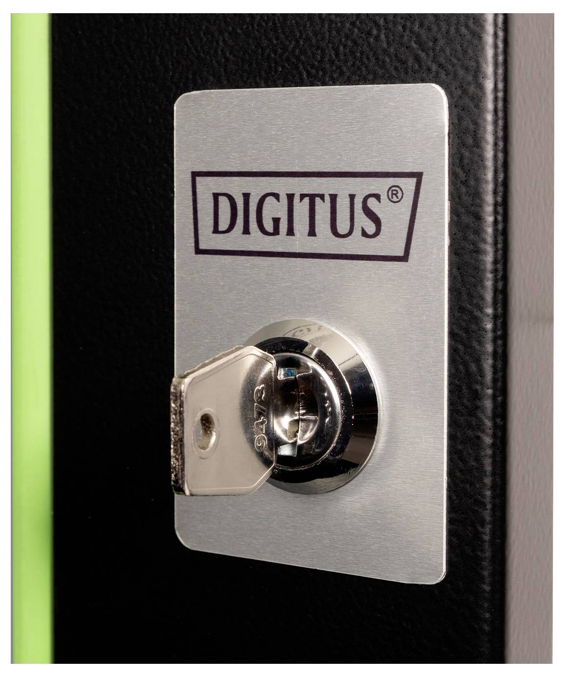 En nyckel införd i ett lås på en metallplatta märkt "DIGITUS", monterad på en grön och svart yta, vilket tyder på säkrad lagring.