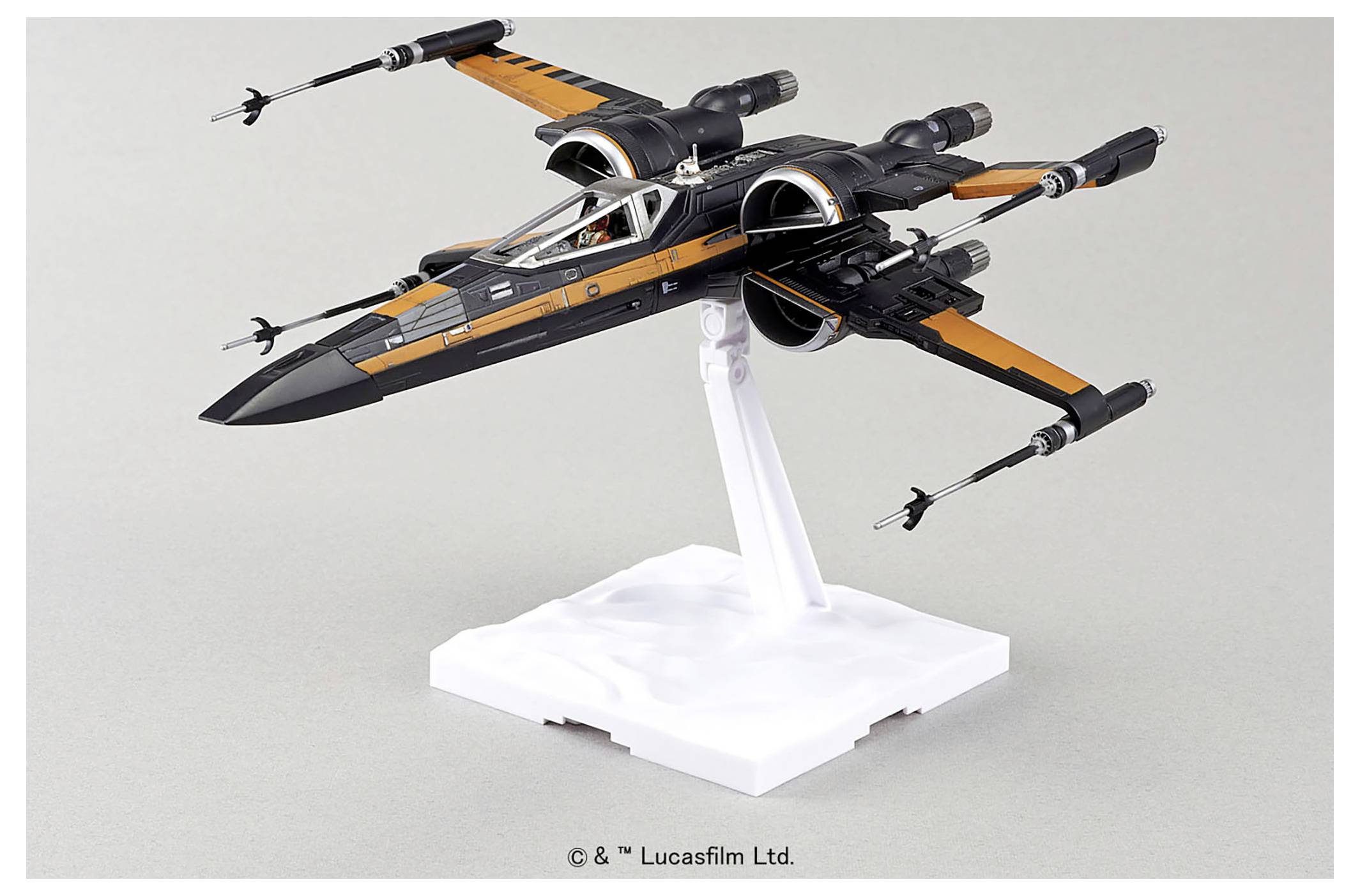 En modell av ett svart och oranget rymdskepp som liknar en "X-wing" från en populär science fiction-serie, placerad på ett vitt ställ.