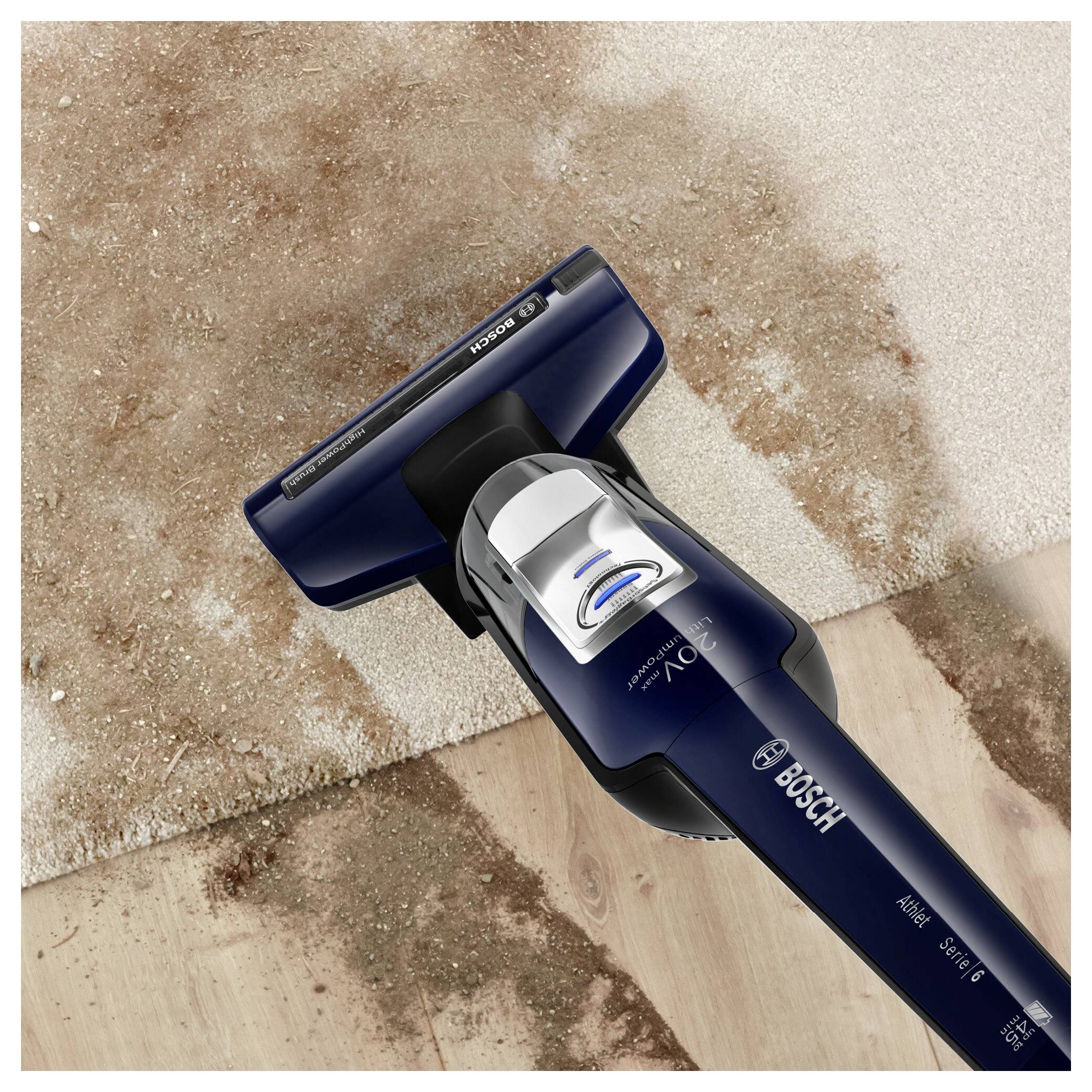 En dammsugare rör sig över en matta och tar effektivt bort smuts och skräp. Apparaten står på ett trägolv intill mattan.