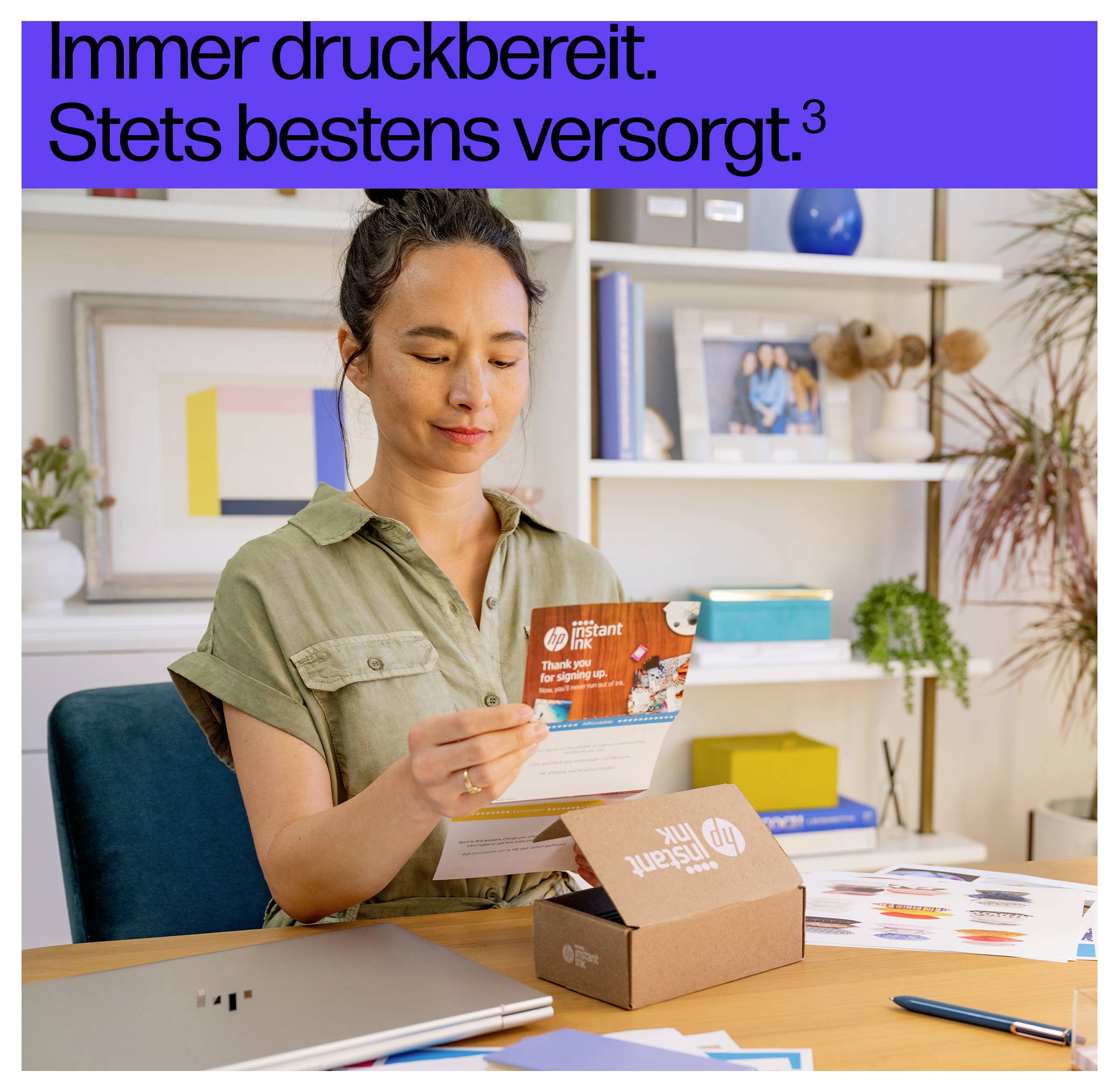 En kvinna sitter vid ett skrivbord och packar upp HP Instant Ink-patroner. En bärbar dator och färgutskrifter syns. Text ovanför lyder 'Alltid utskriftsklar. Ständigt väl försedd.'