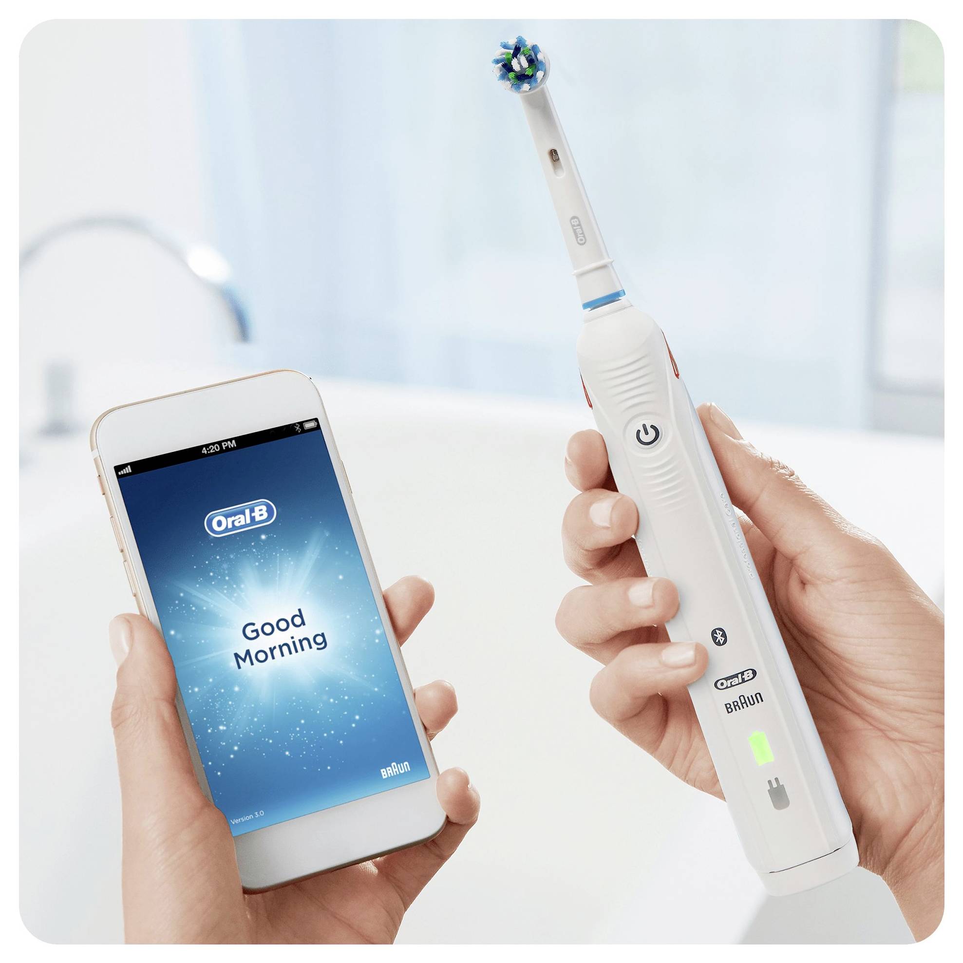 En person håller en Oral-B tandborste i ena handen och en smartphone som visar Oral-B-appen med meddelandet "God morgon" i den andra handen.