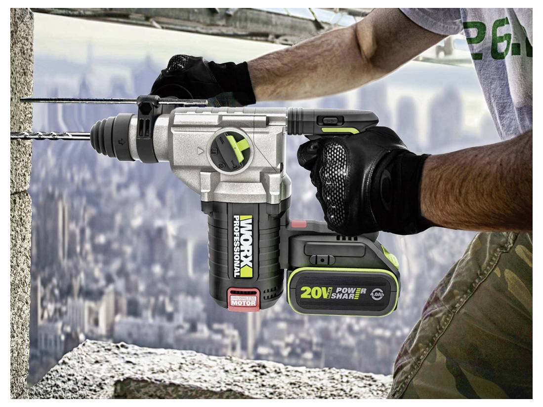 En person använder en Worx 20V elborr för att borra ett hål i en betongvägg, bär handskar och står på en höghusbyggarbetsplats.