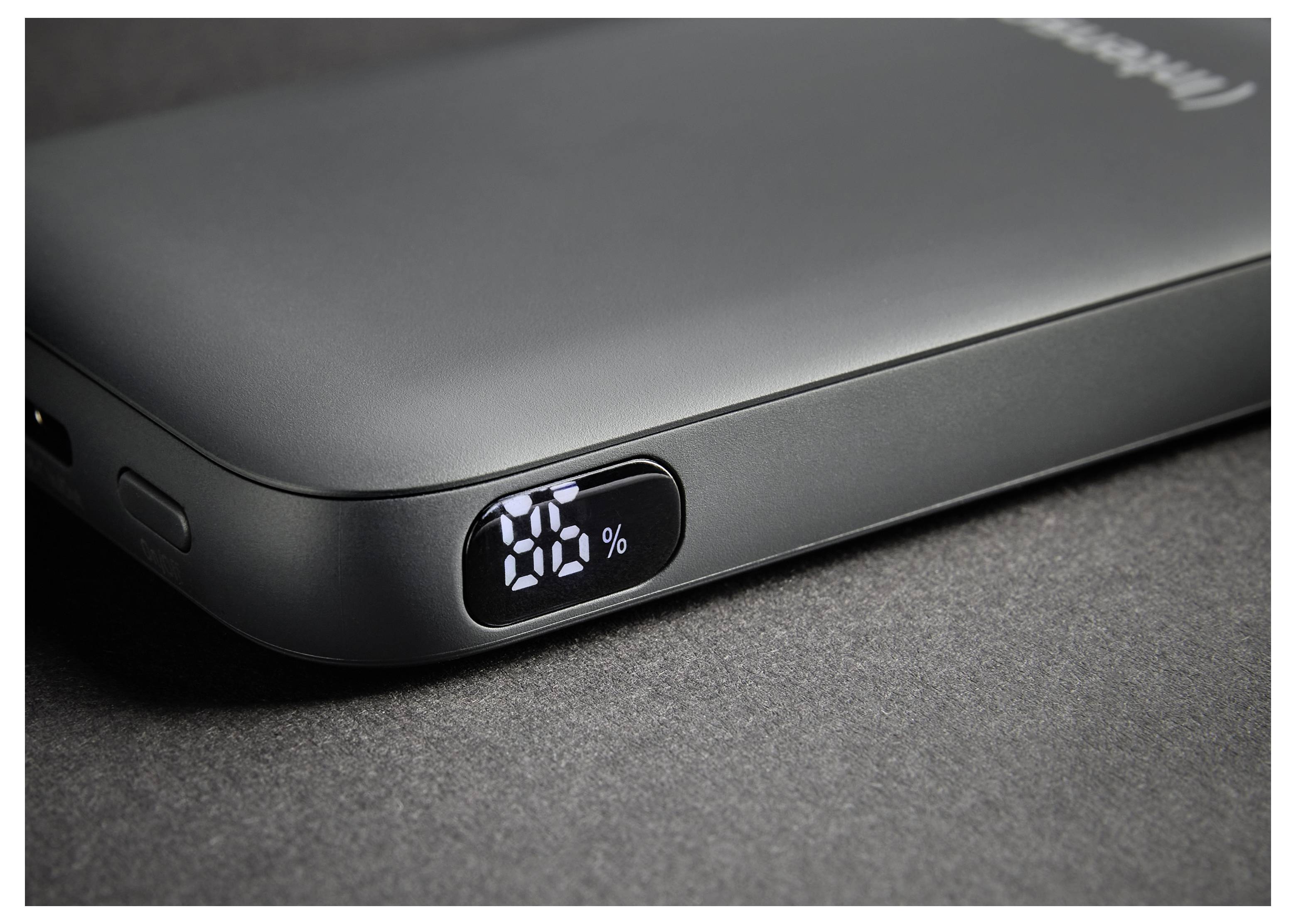 En svart bärbar powerbank på en mörk yta visar "76%" på sin digitala display, vilket indikerar återstående batteriladdning.