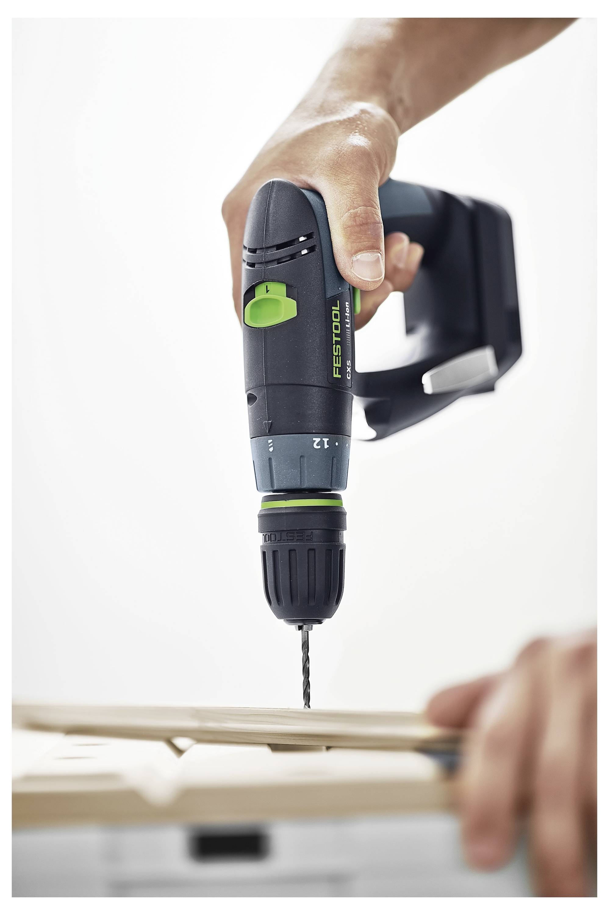 En person använder en trådlös borrmaskin för att driva en skruv in i en träyta, med betoning på verktygets ergonomiska design och kontroll.