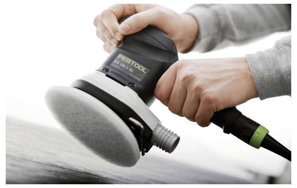 Händer som använder en Festool excenterslip för att polera en yta, vilket visar precisionsarbete och försiktig applicering för en slät finish.