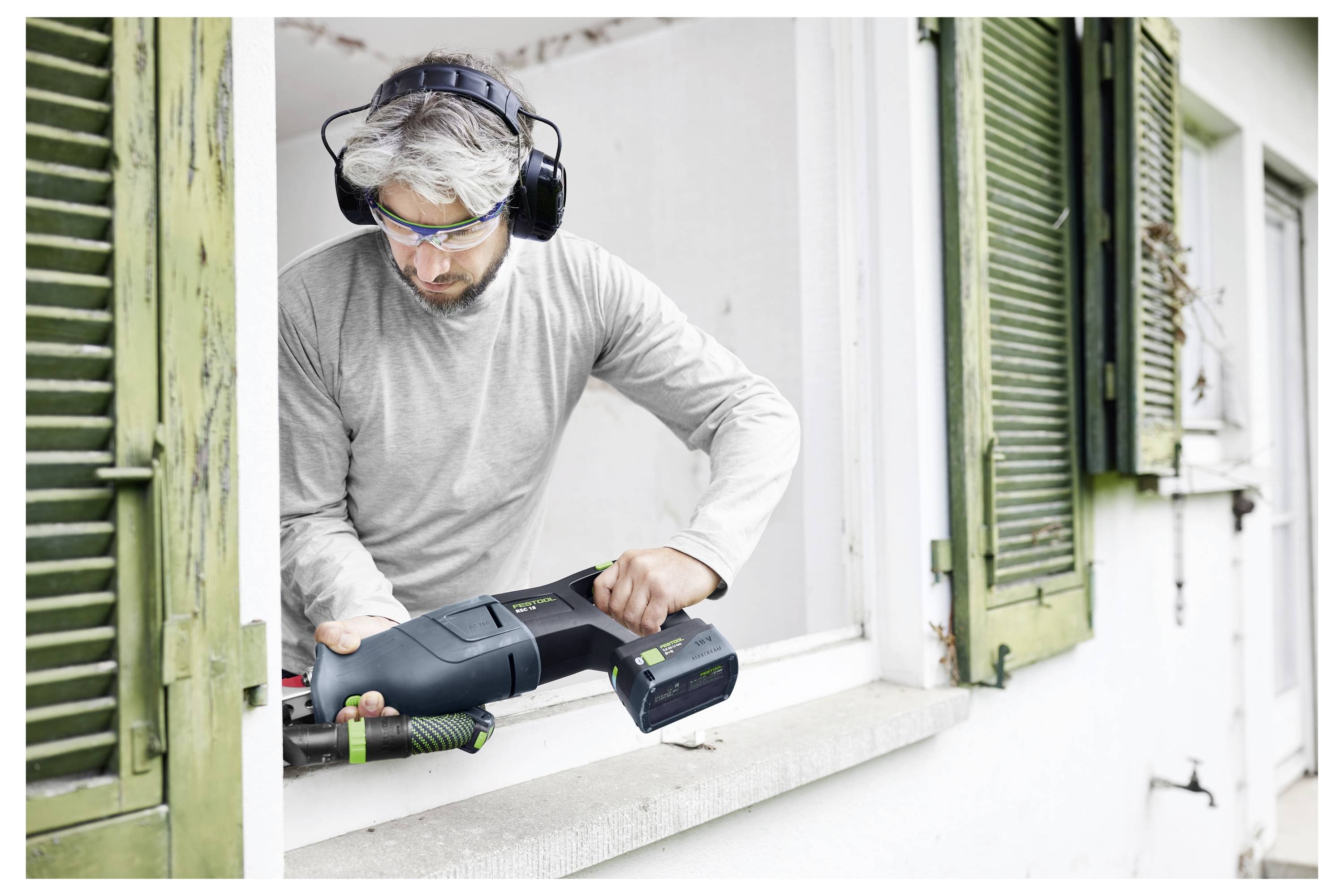 En person använder en Festool elborr för att borra ett hål i en betongyta och demonstrerar en konstruktionsuppgift.