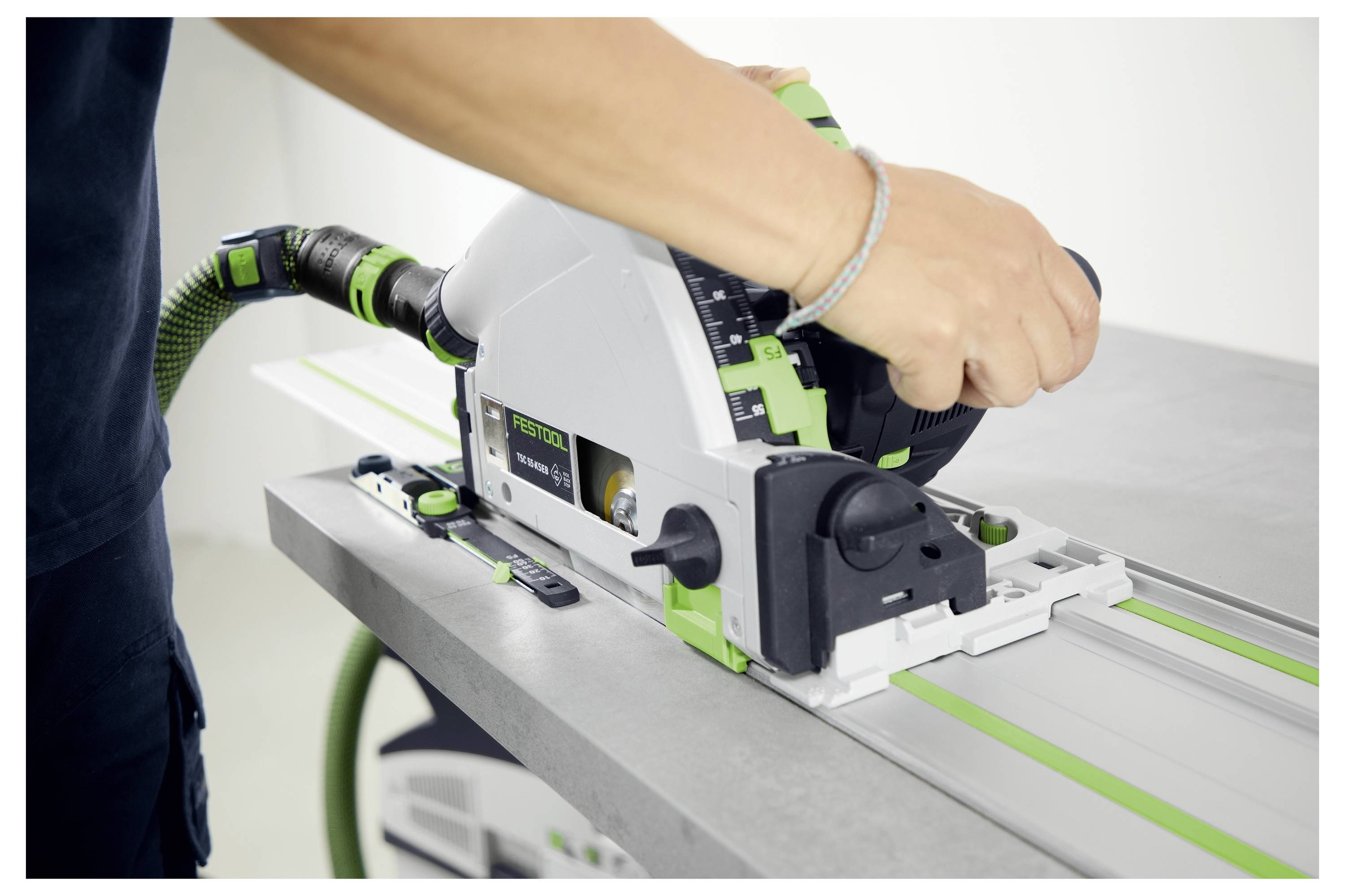 En person använder en Festool spårslip för att skära material på en arbetsbänk och säkerställer exakta, raka snitt med det guidade räilsystemet.