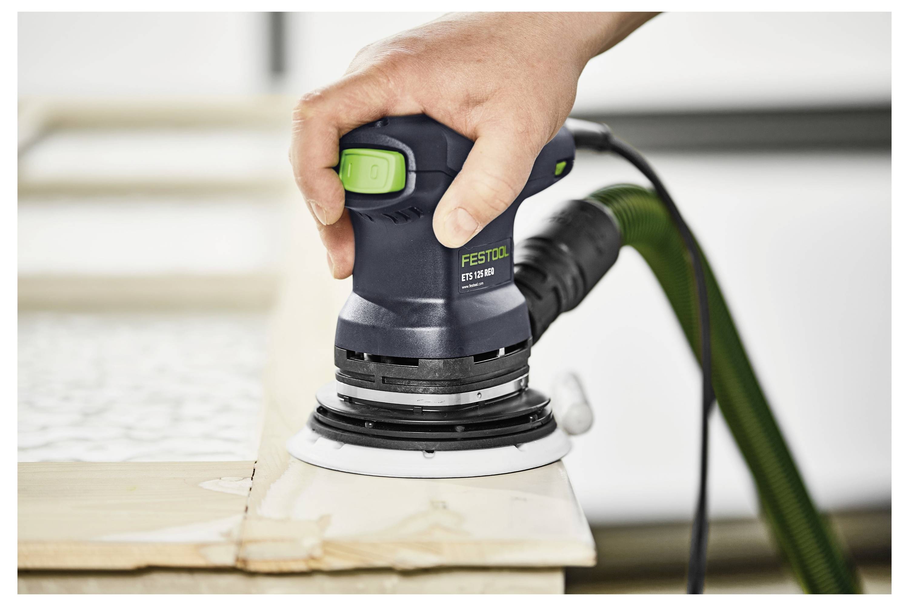 En person använder en triangulär slipmaskin för att slipa en träyta, vilket belyser detalj och precision i träbearbetningsuppgifter.
