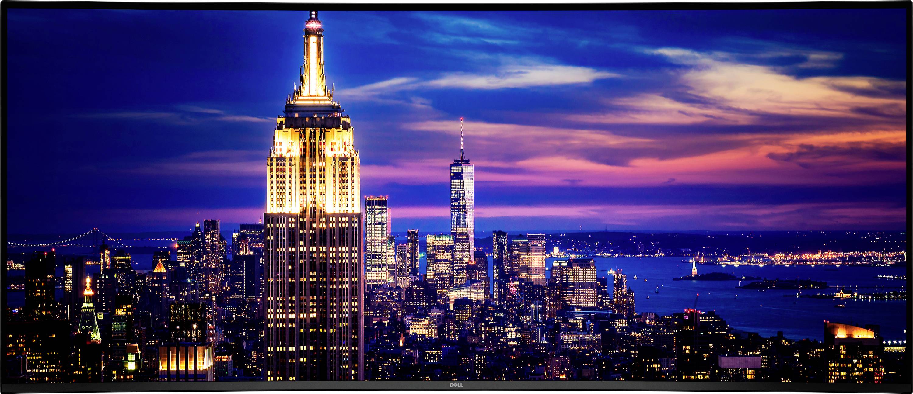 Bilden visar en nattstadsvy av New York City med Empire State Building upplysta i förgrunden och stadssilhuetten i bakgrunden.