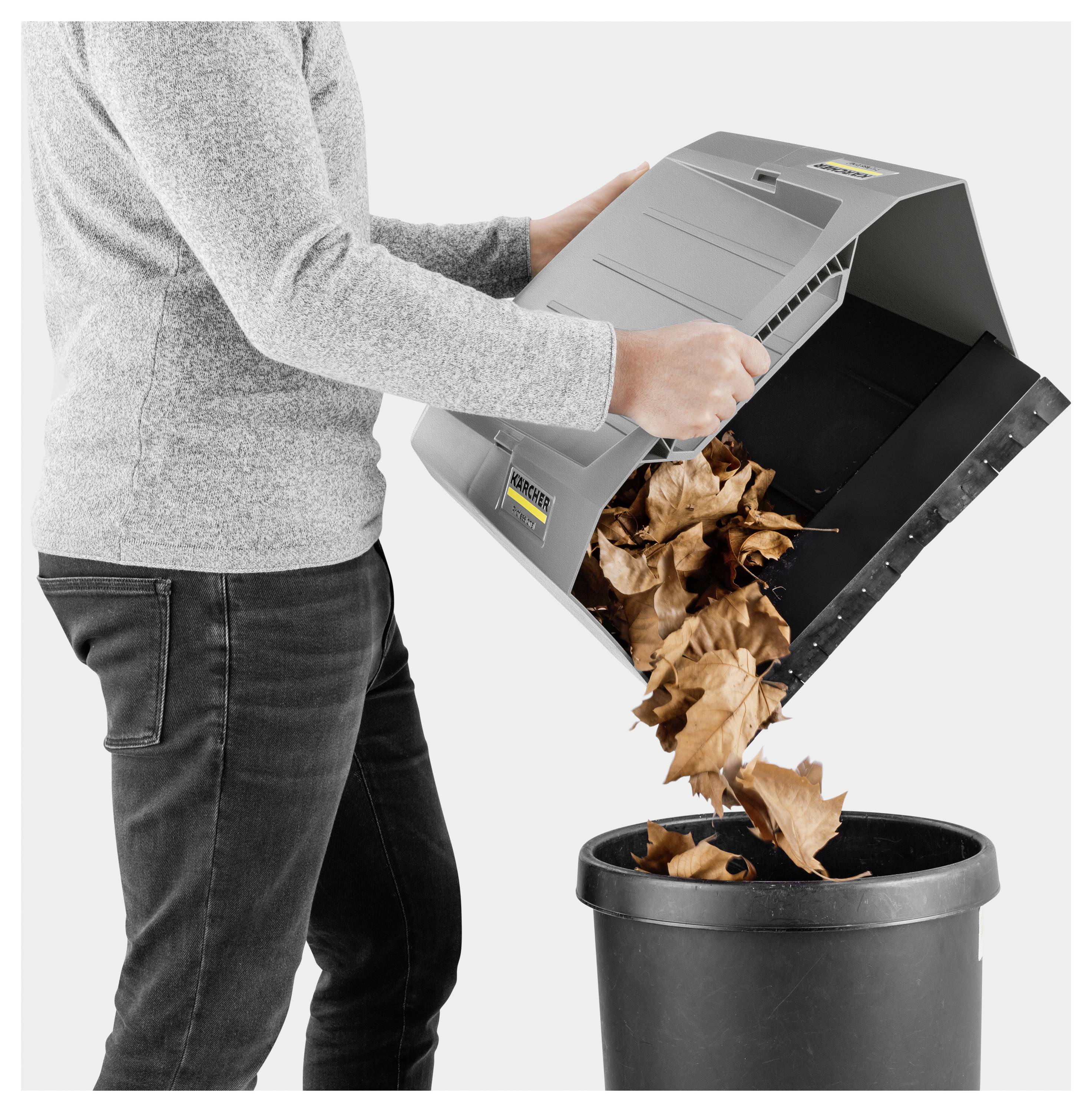En person tömmer torkade löv från en maskin in i en svart behållare och demonstrerar processen för lövinsamling och bortskaffning.