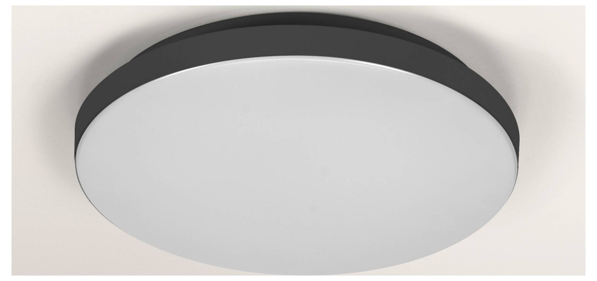 En rund, platt LED-taklampa med vit diffusor och svart kant är monterad på ett vitt tak och ger jämn belysning.