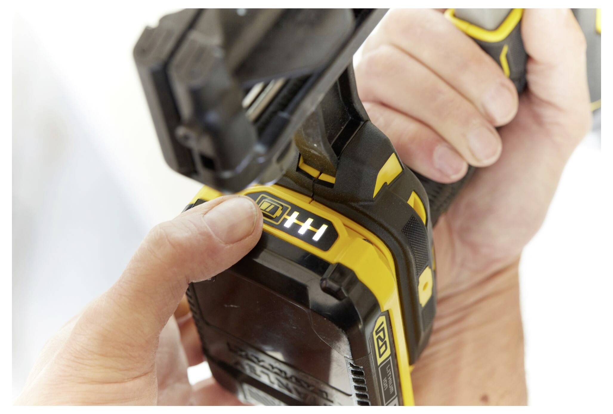 Närbild av en person som byter batteri på ett gult och svart elverktyg, som visar en hand som trycker på batteriets utlösningsknapp.