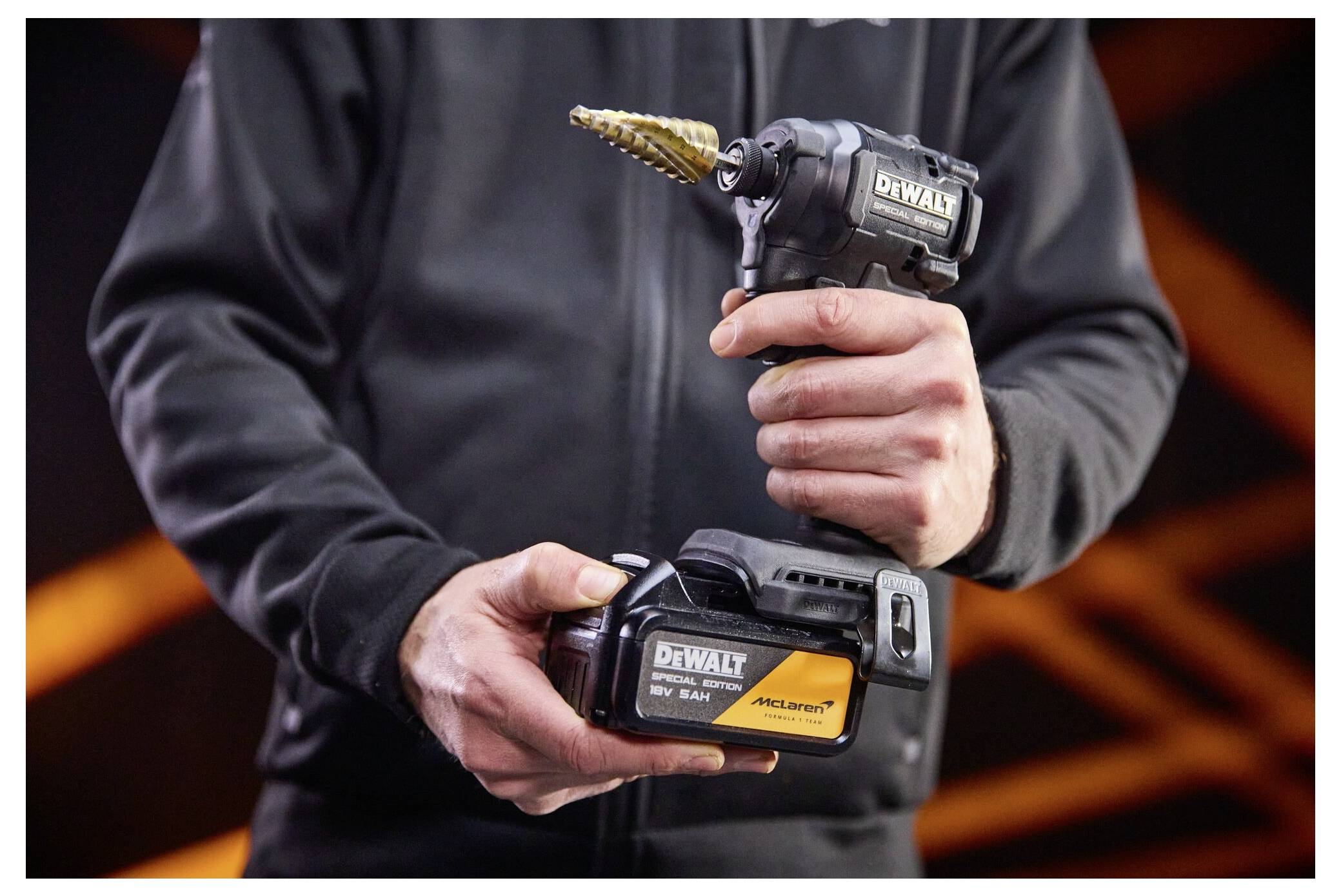 Person som håller en DEWALT trådlös vinkelborrmaskin med en steglind och matchande batteriladdning.